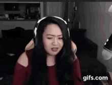 a woman wearing headphones is making a funny face in front of a camera .