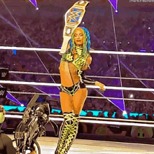 a woman in a wrestling ring is holding a championship belt in the air .