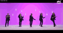 a group of women in suits are dancing together on a purple background .