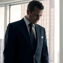 a man in a suit and tie looks down at something