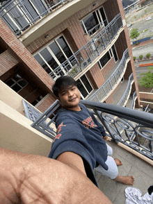 a man taking a selfie on a balcony with a shirt that says ' abercrombie & fitch '