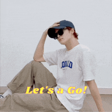 a man wearing sunglasses and a hat says let 's go in yellow letters