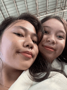 two girls are posing for a picture together and one has a necklace around her neck