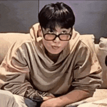 a man wearing glasses is sitting on a couch .