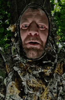 a man with a beard wearing a camouflage hooded jacket