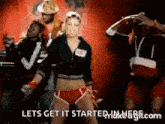 a group of people are dancing in front of a sign that says lets get it started