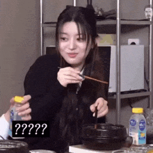 a woman is eating food with chopsticks and a bottle of water .