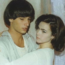a man is holding a woman in his arms in front of a window .
