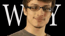 a young man with glasses is smiling in front of the letter w