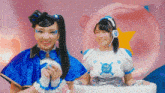 two girls in blue and white costumes are sitting next to each other on a pink background .
