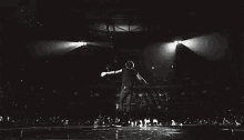 a man is standing on a stage in front of a crowd with his arms outstretched .