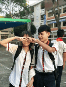 a boy and a girl are making a heart with their hands and the girl has the letter c on her shirt