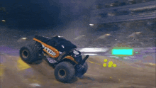 a monster truck is going down a dirt track in front of a crowd and a sign that says ' monster jam ' on it