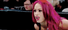a woman with pink hair is making a funny face while sitting in a ring .