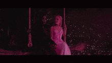 two women are sitting on a swing in the dark