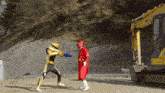 a man in a red suit stands in front of a yellow excavator