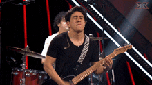 a man playing a guitar in front of a microphone with an x on it