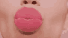a close up of a woman 's lips making a kiss on a pink background .