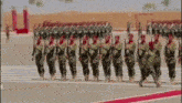 a group of soldiers are marching in a parade in a line .
