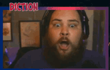 a man with a beard is wearing headphones and making a funny face while playing a video game .