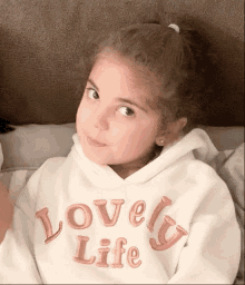 a little girl is wearing a white sweatshirt that says lovely life