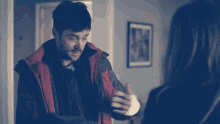 a man in a red jacket is holding a woman 's hand