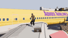 a man is standing on the wing of a yellow adios airlines plane