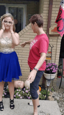 a woman in a red shirt stands next to a girl in a blue skirt in front of a sign that says pumpkin