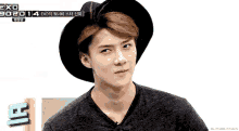 a young man wearing a black hat and a black shirt with exo 902014 on the bottom right