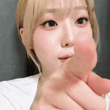 a close up of a woman making a heart with her finger