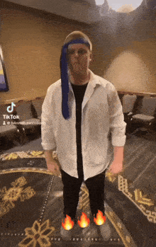 a man in a white shirt and black pants is standing in front of a tiktok sign