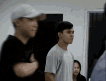 a group of people are standing in a room and one of them is wearing a white hat .