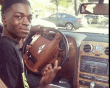 a man is sitting in a bentley car and giving the middle finger