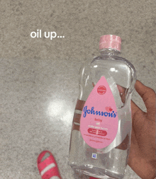 a person holding a bottle of johnson 's baby oil in their hand
