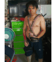 a shirtless man is standing in front of a green dresser with a fan