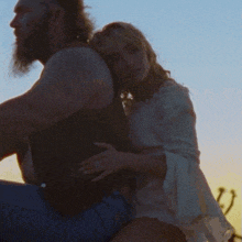 a woman sits on the back of a man on a scooter