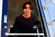 a man in a black shirt is standing in a doorway with a sign that says kim on it