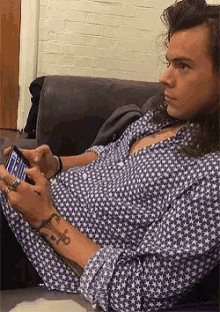 a man is sitting on a couch looking at his phone