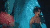 a woman in a green dress is swimming under water