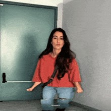 a woman in a red shirt and blue jeans is dancing