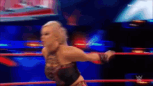 a woman is standing in a wrestling ring with the letter w on the bottom right