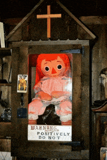 a doll in a wooden box with a sign that says " warning positively do not "