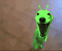 a green dog with antennas on its head is standing on a brown floor