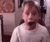 a young boy is making a surprised face in a room .