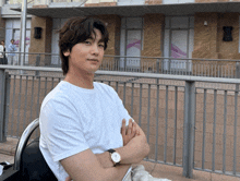 a man with his arms crossed wearing a watch looks at the camera