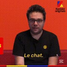 a man wearing glasses and a black shirt that says le chat on it