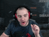 a man wearing headphones and a t-shirt is making a funny face while talking into a microphone .