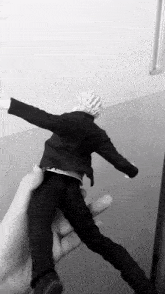 a black and white photo of a person holding a figurine of a man in a suit