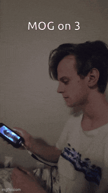 a young man is playing a video game with the words mog on 3 written above him
