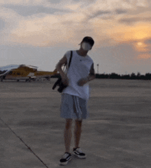a man wearing a mask and a hat is standing on a runway